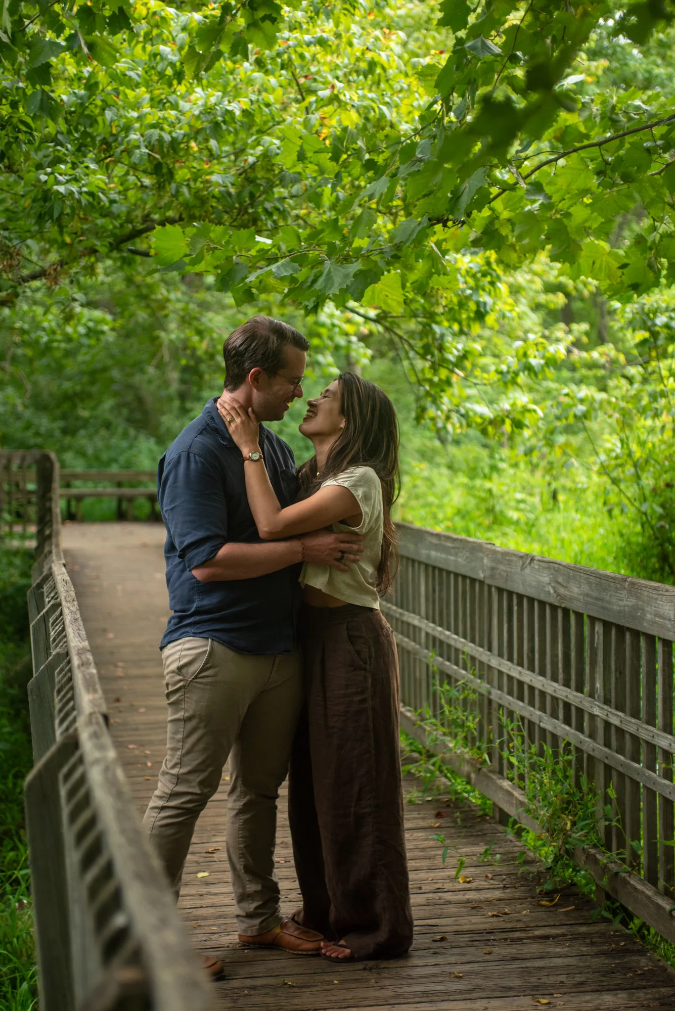 A couple close together on a wooded bridge in Asheville