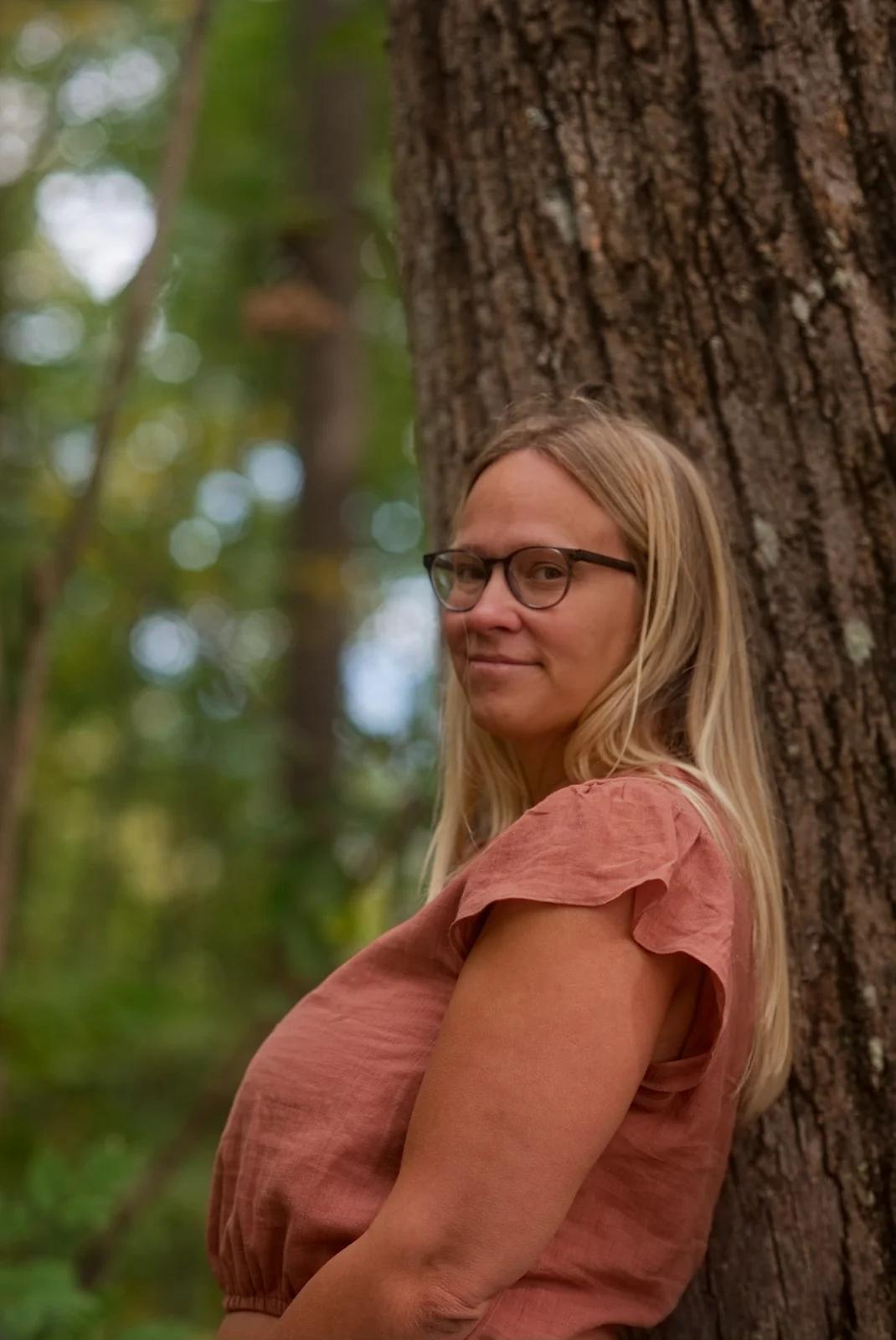 Steph Jensen leaning against a tree in the woods outside Asheville
